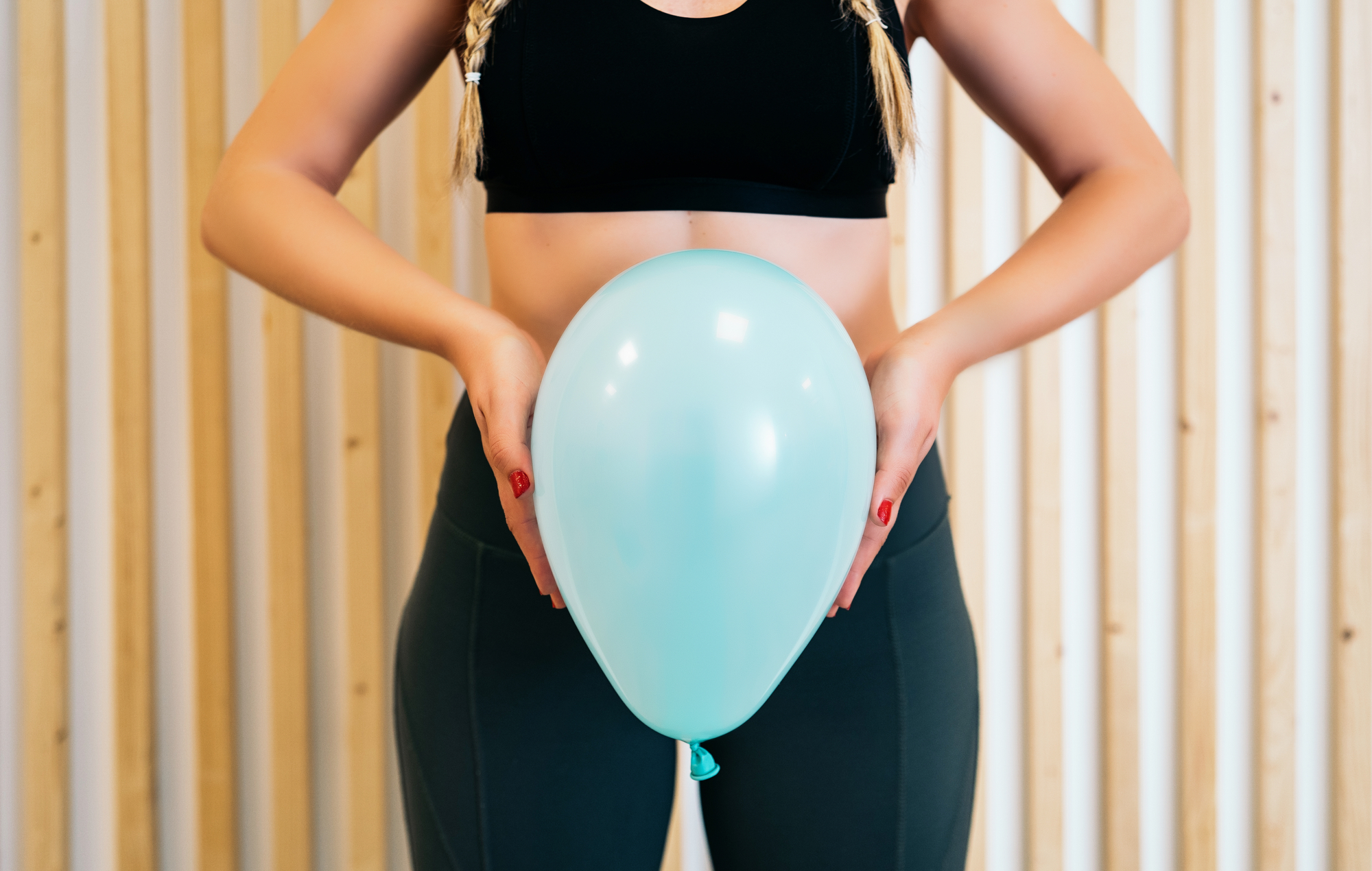 Alooro Blog Close up of a young woman holding a balloon to explain the diaphragm zones, core and pelvic floor. Pelvic floor exercises explained