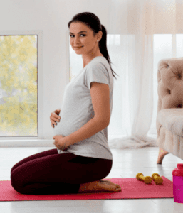 Pregnant woman in a yoga mat holding her tummy